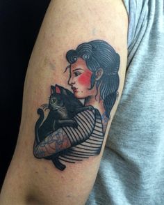 a woman with a cat tattoo on her arm is holding it up to her chest