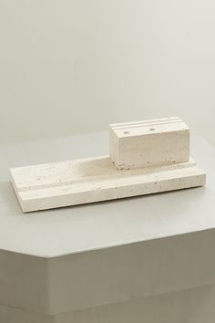 a small block of concrete sitting on top of a table next to a white wall