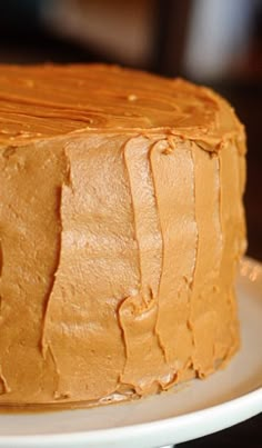 a close up of a frosted cake on a white plate with brown icing