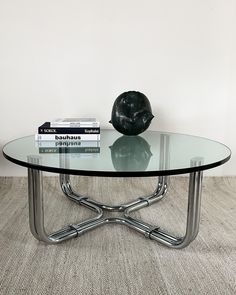 a glass table topped with books and a black sculpture