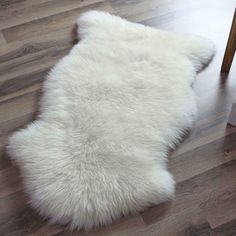 a white sheepskin rug sitting on top of a wooden floor next to a plant