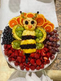 a plate full of fruit with a statue made out of it