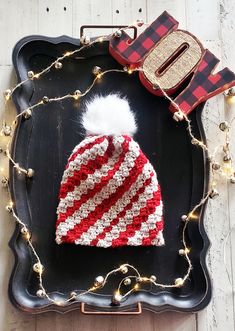 a red, white and blue knitted hat sitting on top of a black tray