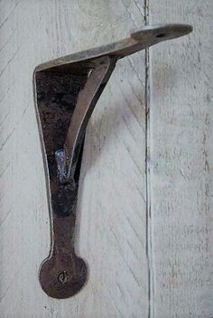 an old metal hook on the side of a white wooden door with rusted handles