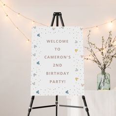 a welcome sign sitting on top of a easel next to a vase with flowers