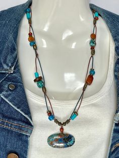 Shattuckite and Chrysocolla Cabochon wire wrapped with a Carnelian bead crown on bronze and turquoise 1mm leather cord. Mated with African Turquoise, Amber, Buffalo Bone, Carnelian, turquoise dyed bone, blue pony beads, and bronze metal beads. Bronze toggle to close. Cabochon is 1 5/8 x 3/4. Total necklace length is 24" with cabochon. No lead or nickel used. Please use the Last On, First Off approach. Stones discolor with lotions, perfumes, hairspray, sweat, chlorine, even some soaps, and will break if dropped. Casual Turquoise Beaded Necklaces For Festival, Adjustable Artisan Turquoise Necklace, Handmade Bohemian Turquoise Chrysocolla Necklace, Bohemian Blue Turquoise Chrysocolla Necklace, Bohemian Chrysocolla Beaded Necklaces For Jewelry Making, Bohemian Turquoise Chrysocolla Necklace, Bohemian Chrysocolla Necklace, Bohemian Chrysocolla Beaded Necklace In Turquoise, Bohemian Blue Chrysocolla Beaded Necklace