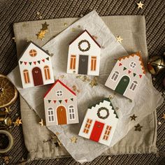 small wooden houses decorated with christmas decorations on top of a cloth covered napkin next to scissors and other items