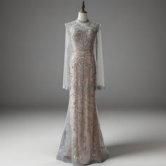 Step into a world of elegance and sophistication with our Silver Grey Embellished Long Sleeve Dress. This exquisite evening gown is designed to make a lasting impression at any formal event. Featuring a high neck and sheer long sleeves, this dress is adorned with intricate beading and shimmering sequins that catch the light beautifully. The fitted silhouette accentuates your curves, providing a flattering and graceful look. Intricate Beading and Sequins: The dress is beautifully adorned with detailed beading and sparkling sequins, creating a dazzling effect that ensures you stand out. High Neck and Sheer Long Sleeves: The elegant high neck and sheer long sleeves add a touch of sophistication, perfect for formal occasions and evening events. Flattering Fitted Silhouette: The fitted design o Elegant Embellished Gown For Banquet, Elegant Floor-length Hand Embellished Gown, Elegant Floor-length Hand Embellished Dress, Hand Embellished Gown For Prom Evening, Elegant Hand Embellished Floor-length Gown, Formal Hand Embellished Evening Dress With Fitted Bodice, Formal Evening Dress With Hand-embellished Fitted Bodice, Elegant Hand Embellished Gown For Prom Season, Elegant Hand Embellished Gown For Prom