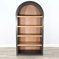 a wooden book shelf sitting on top of a hard wood floor next to a white wall