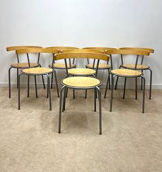 six wooden chairs are lined up against the wall in a room with carpeted flooring