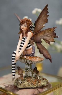 a fairy figurine sitting on top of a mushroom