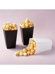 two black containers filled with popcorn next to each other