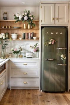 a kitchen with white cabinets and flowers on the shelves