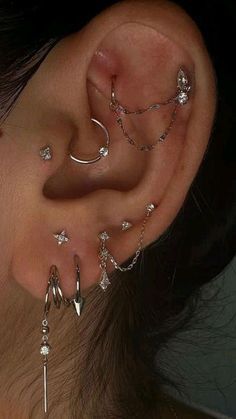 a woman's ear with several different piercings on her left side and one behind the ear