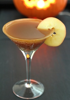 an apple sitting on top of a glass filled with liquid next to a jack - o'- lantern