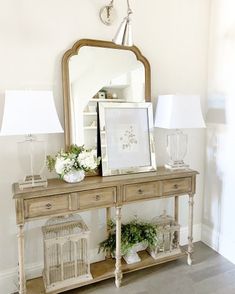 a table with a mirror, lamp and flowers on it