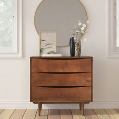 a wooden dresser with a mirror and vase on it in front of a white wall