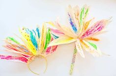 two colorful paper flowers on a white surface