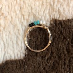 a close up of a ring on top of a fur surface with beads and stones