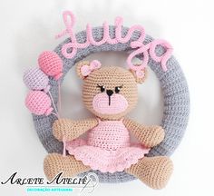 a crocheted teddy bear sitting in front of a sign that says jujura