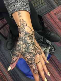 a woman's hand with an intricate tattoo on it