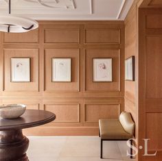 a dining room with wood paneling and art work on the wall behind the table