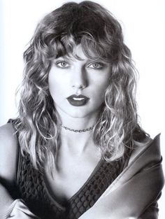 a black and white photo of a woman with long curly hair wearing a choker