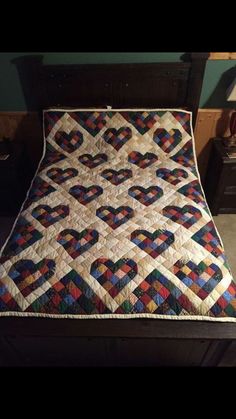 a bed with a quilt on top of it in the middle of a room next to a night stand