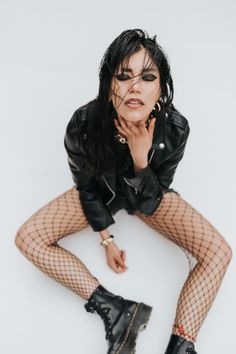 a woman in fishnet stockings and black boots posing for the camera with her hands on her face