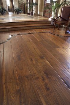 an empty room with wooden flooring and steps leading up to the second story area