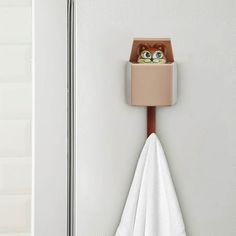 a towel holder with a cat head in it and a white towel hanging from the wall