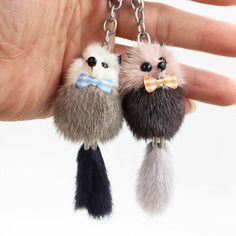 two small furry animals wearing bow ties are being held by a person's hand