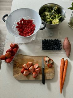 fruits and vegetables are arranged on a cutting board next to a bowl of broccoli