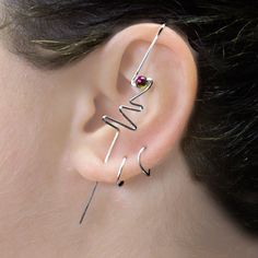 a woman with ear piercings that have the word love written on them and an arrow in the middle