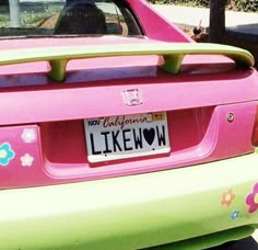 a pink and green car with flowers painted on the rear bumper, parked in a parking lot