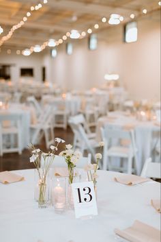 the tables are set up with white linens and centerpieces for an elegant reception