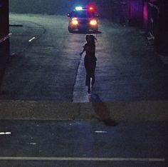 a woman is walking down the street at night