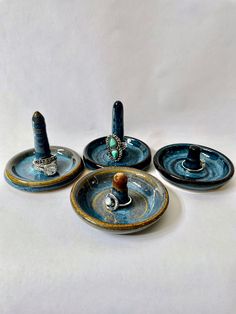 three blue plates with rings on them sitting next to each other in front of a white background