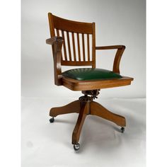 a wooden office chair with green leather seat