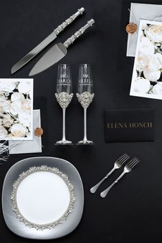 the table is set with silverware and white flowers on it, including two champagne flutes