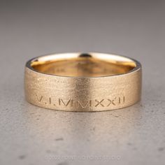 a gold wedding band with roman numerals on it