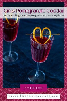 two glasses filled with red liquid and orange peel garnished with an orange slice