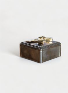 a small metal box with two gold - plated scissors on it's lid