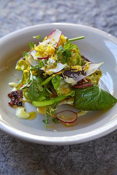 a white plate topped with salad and greens