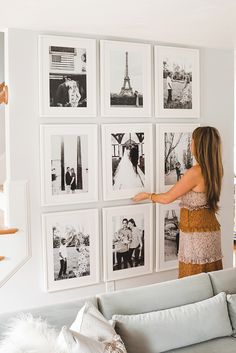 a woman is hanging pictures on the wall