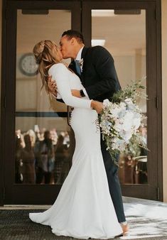 a bride and groom kissing in front of an entrance