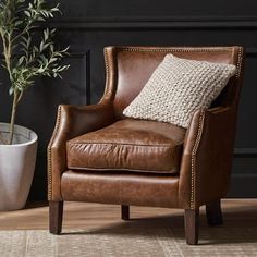 a brown leather chair sitting next to a potted plant