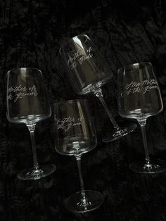 three wine glasses sitting next to each other on a black tableclothed surface with writing