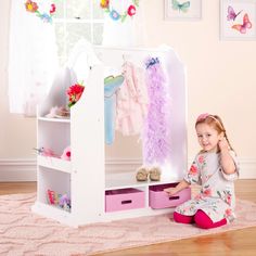 a white doll house with pink and purple accessories on it's shelves in front of a window