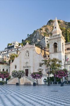 an old church on the side of a hill with flowers growing out of it's windows